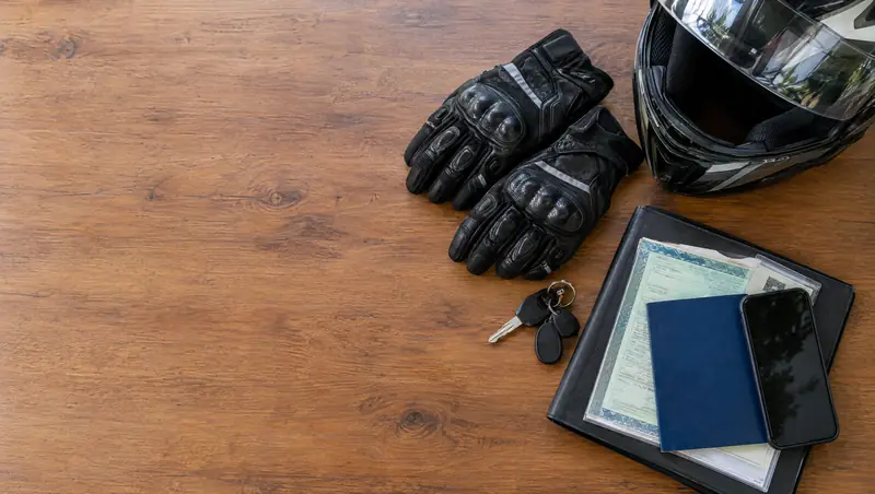 Documentos de motocicleta e capacete organizados sobre uma mesa (imagem ilustrativa)